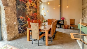 A dining area with a wooden table and chairs, a colorful rug, hanging pendant lights, and a textured wall. - Villa Isobel (Vila Verde)
