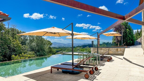 A poolside area with a view of the landscape, outdoor furniture, and umbrellas. - Villa Isobel (Vila Verde)