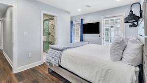 A bedroom with a bed, a bedside lamp, and a window with blinds. - Conveniently Located Contemporary 6 Bed/6 Bath 15 Min to Downtown (Metairie)