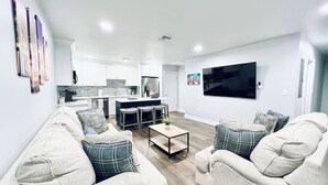 A modern living room with a sofa set, a coffee table, and a TV mounted on the wall. - Conveniently Located Contemporary 6 Bed/6 Bath 15 Min to Downtown (Metairie)