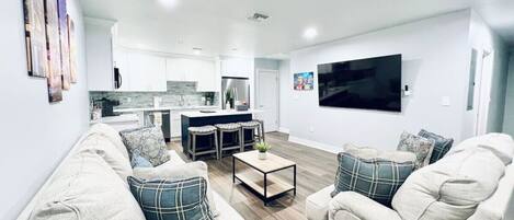 Una sala de estar moderna con un conjunto de sofá, una mesa de centro y un televisor montado en la pared.