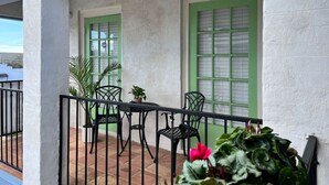 A balcony with a table and chairs, green-framed windows, and potted plants. - Conveniently Located Contemporary 6 Bed/6 Bath 15 Min to Downtown (Metairie)