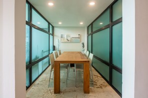 Conference room with a long table and chairs, large windows, and a painting on the wall.