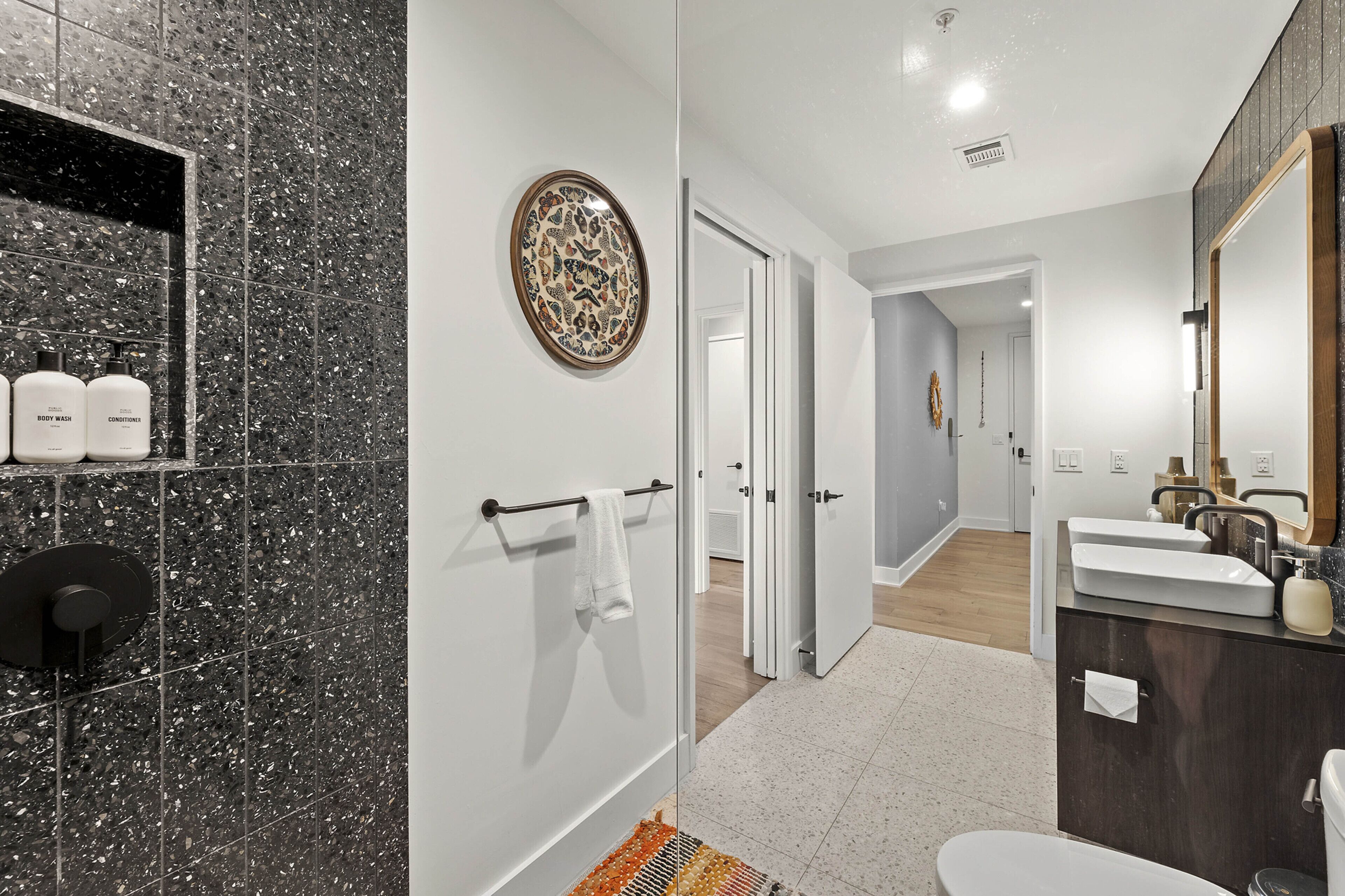 A modern bathroom with a marble shower, a large mirror, and a white sink.