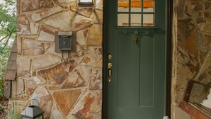 A stone exterior with a green door, a lantern, and a potted plant. - NEW! Off to the races: Stay at the spacious Woodlawn Tudor, close to Oaklawn! (Hot Springs)