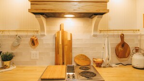 A kitchen with wooden cabinets, a stove, and various kitchen utensils. - NEW! Off to the races: Stay at the spacious Woodlawn Tudor, close to Oaklawn! (Hot Springs)