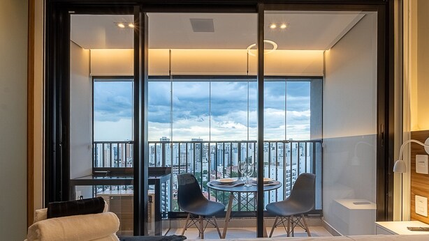 Een modern balkon met uitzicht over de stad, een eettafel, twee stoelen en een bank.