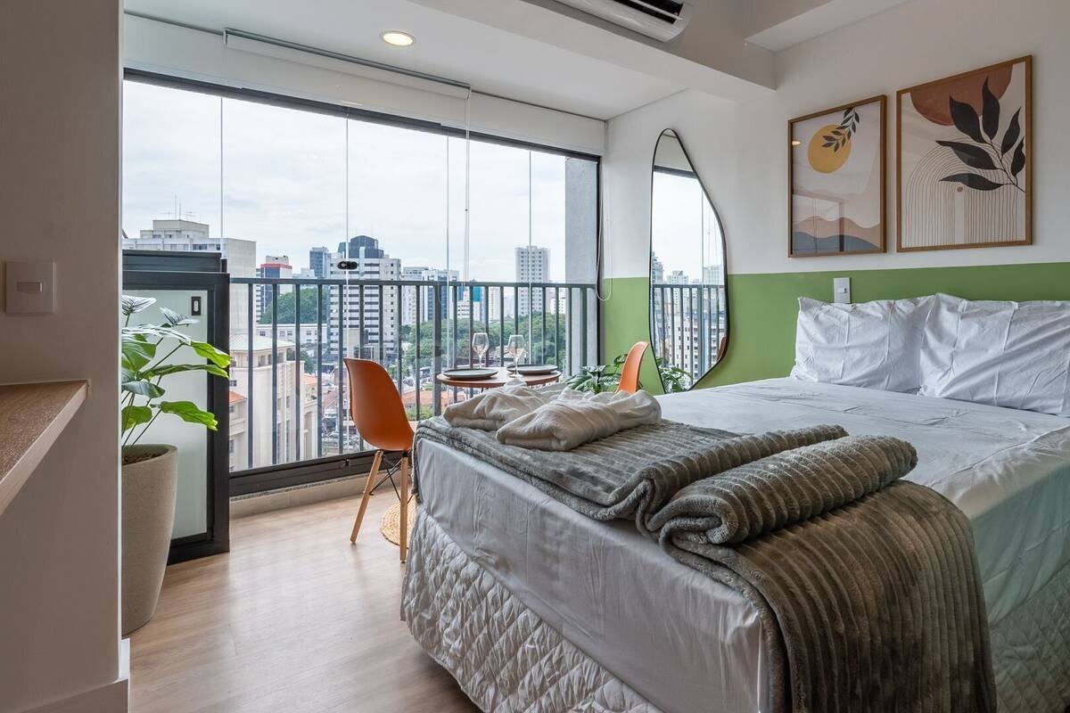 Une chambre d’hôtel moderne avec un grand lit, un mur d’accent vert et un balcon offrant une vue sur la ville.