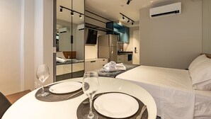 Een hotelkamer met een bed, een eettafel gedekt met borden en glazen, een spiegel en een airconditioning.