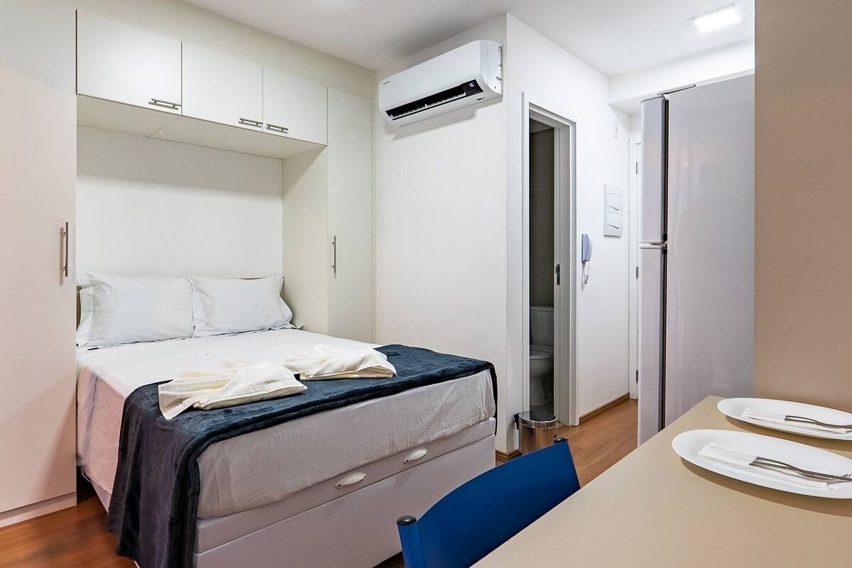 Une petite chambre à coucher comprenant un lit, une petite table avec des assiettes et une chaise.
