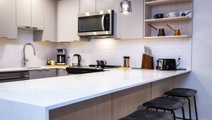 A modern kitchen with a large island, stainless steel appliances, and bar stools. - Separate Reality By Revelstoke Vacations (Revelstoke)