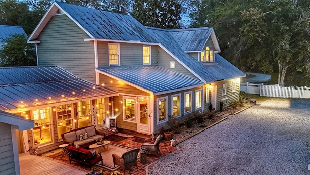 A two-story house with a covered porch, outdoor seating, and string lights.