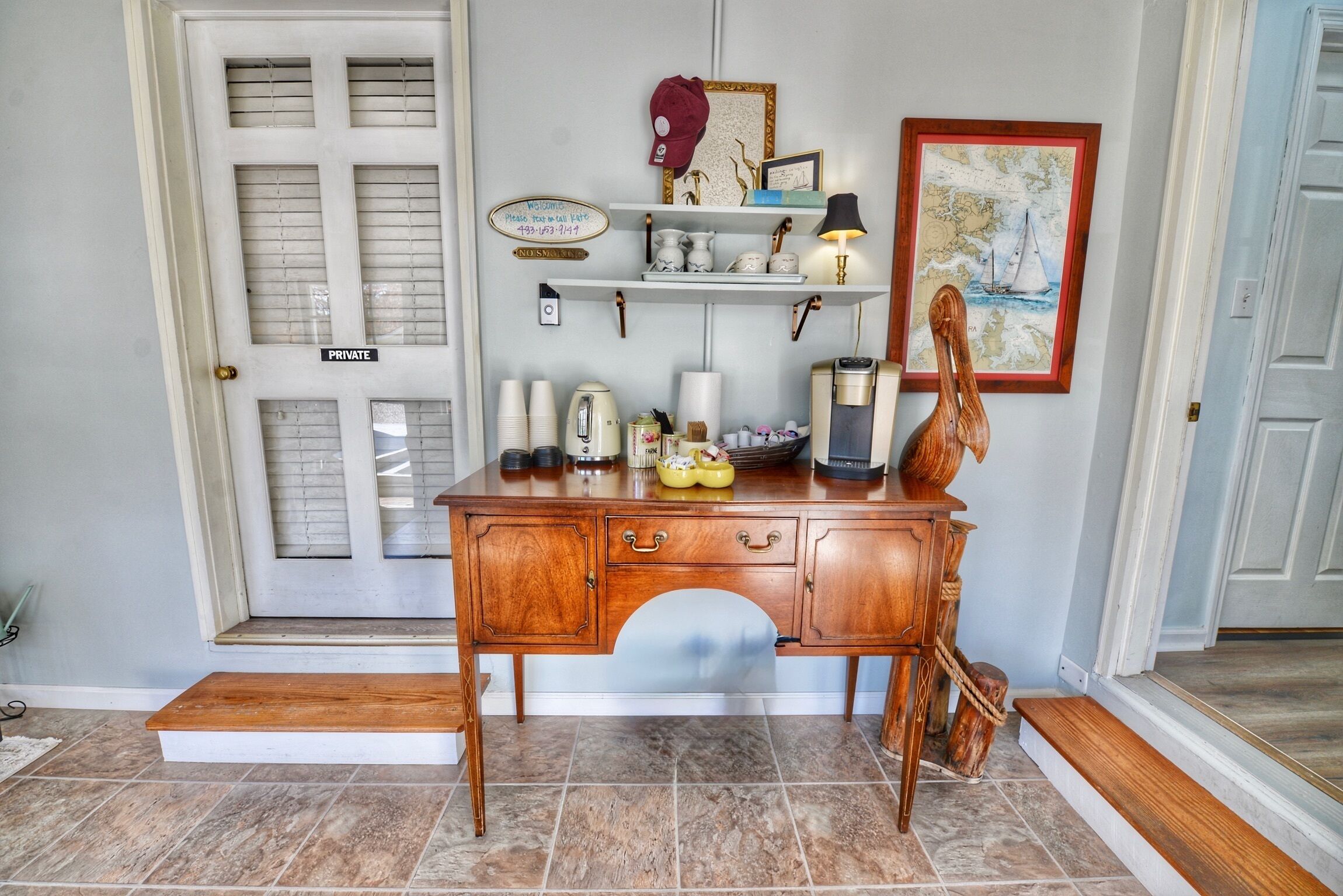 A wooden desk with drawers and shelves, a map, and a lamp.
