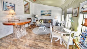 A cozy room with a wooden dining table, a sofa, and a ceiling fan.