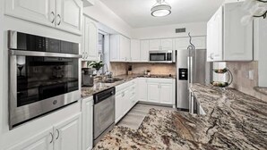Una cocina moderna con armarios blancos, electrodomésticos de acero inoxidable y encimera de granito.