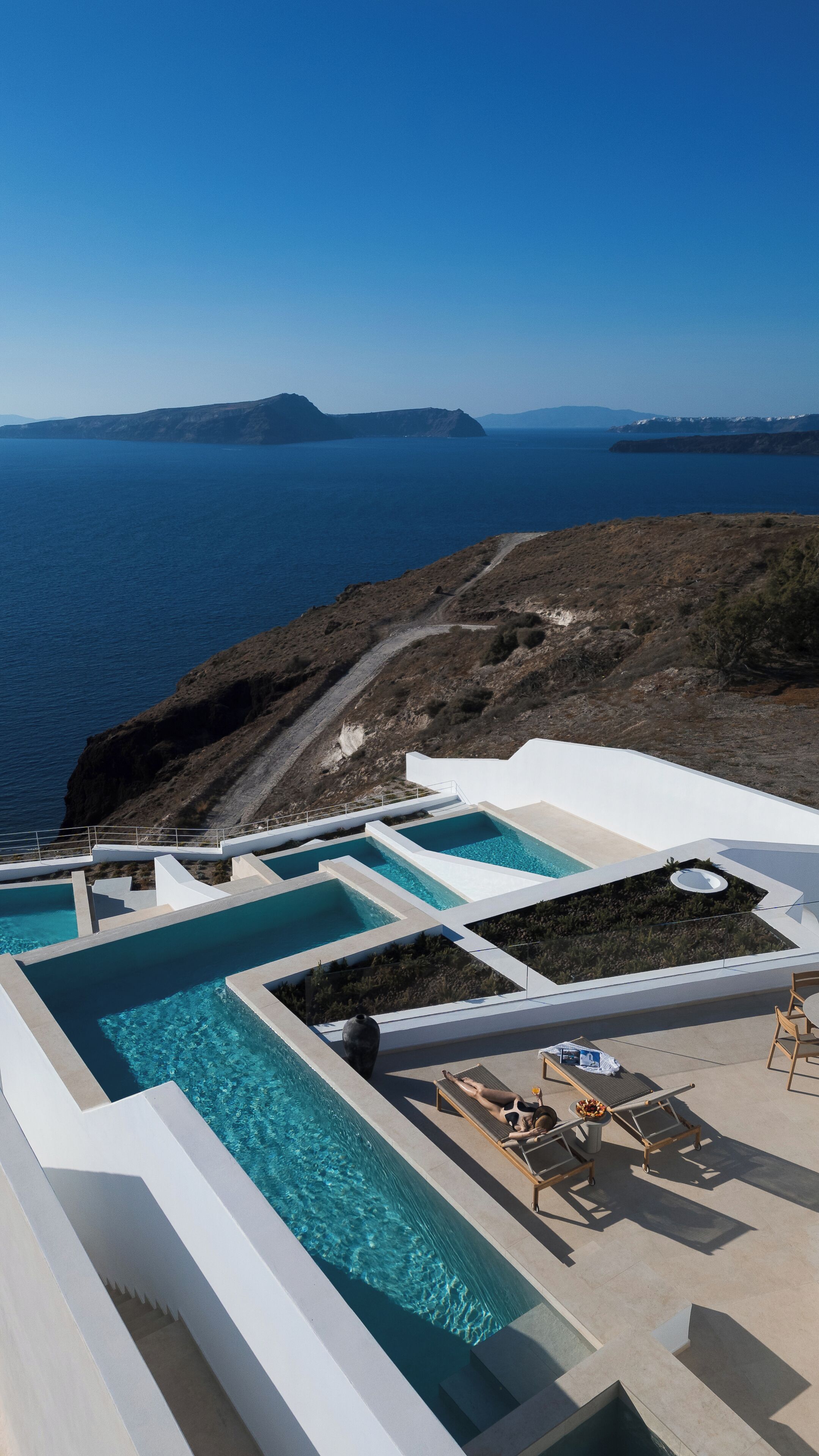 A pool area with multiple sections and a view of the sea and distant islands.