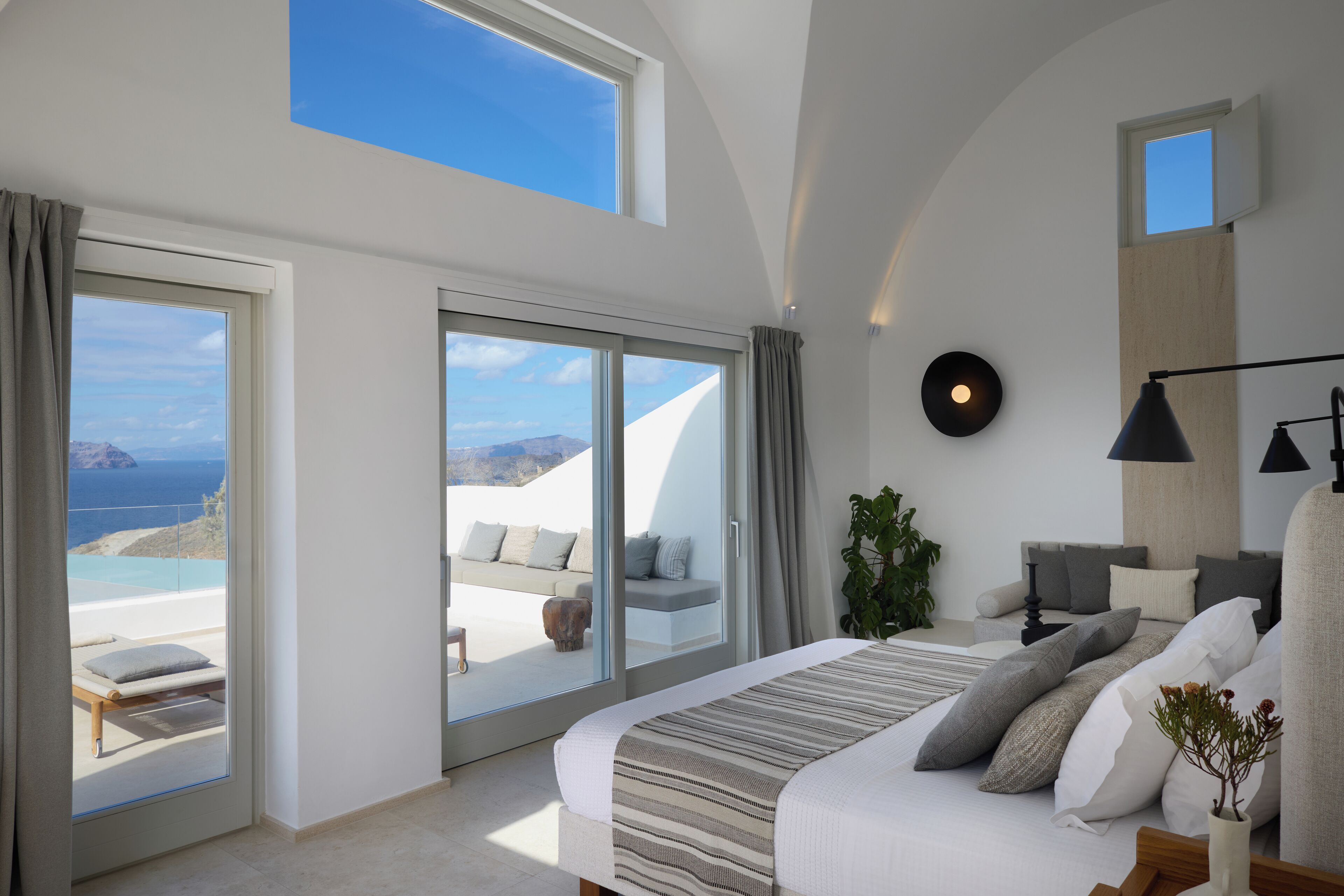 A modern bedroom with a large bed, a view of the sea, and a skylight.