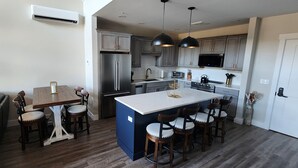 A modern kitchen with a central island, built-in appliances, and a dining area with a sofa and chairs. - Village sunset ski in/ ski out condo on Cranmore Mountain  (Conway)