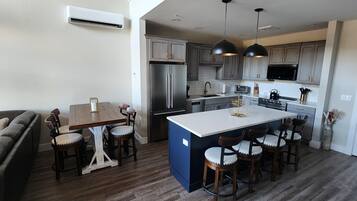 A modern kitchen with a central island, built-in appliances, and a dining area with a sofa and chairs.