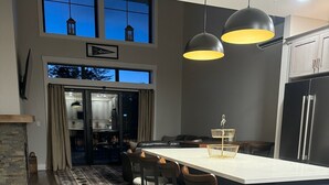 A modern kitchen with a central island, dark cabinetry, and pendant lighting. - Village sunset ski in/ ski out condo on Cranmore Mountain  (Conway)