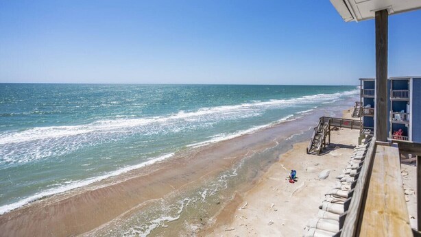 A beach view with a wooden deck and a building with a balcony. - Shore Beats Work - Oceanfront New Balcony 3rd Flr (North Topsail Beach)