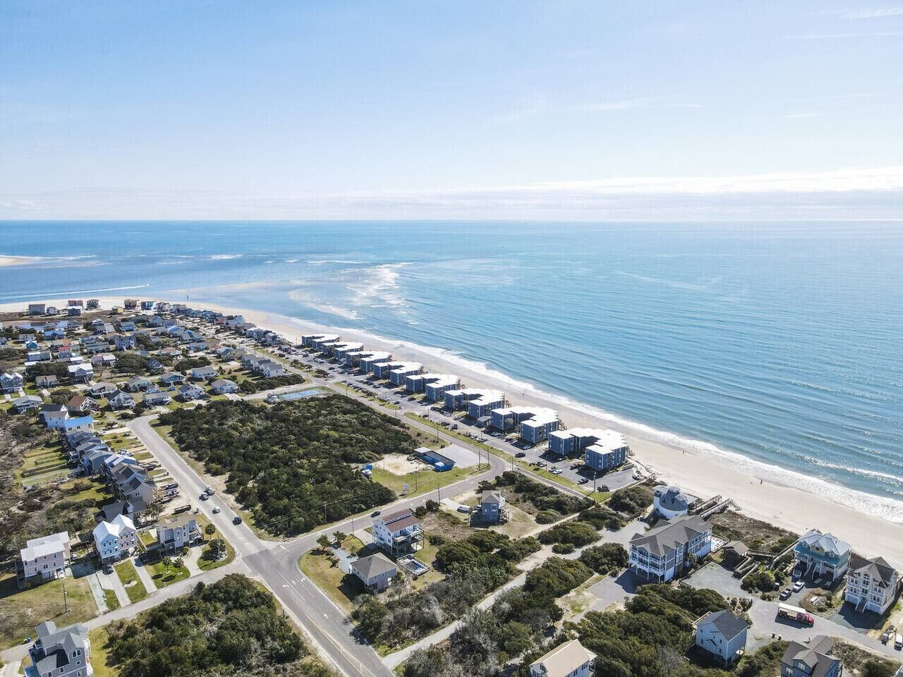 An aerial view of a coastal residential area with houses, roads, and a beach.