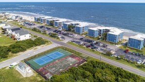 Et kystnært boligområde med ejendomme direkte til stranden, en tennisbane og en parkeringsplads.