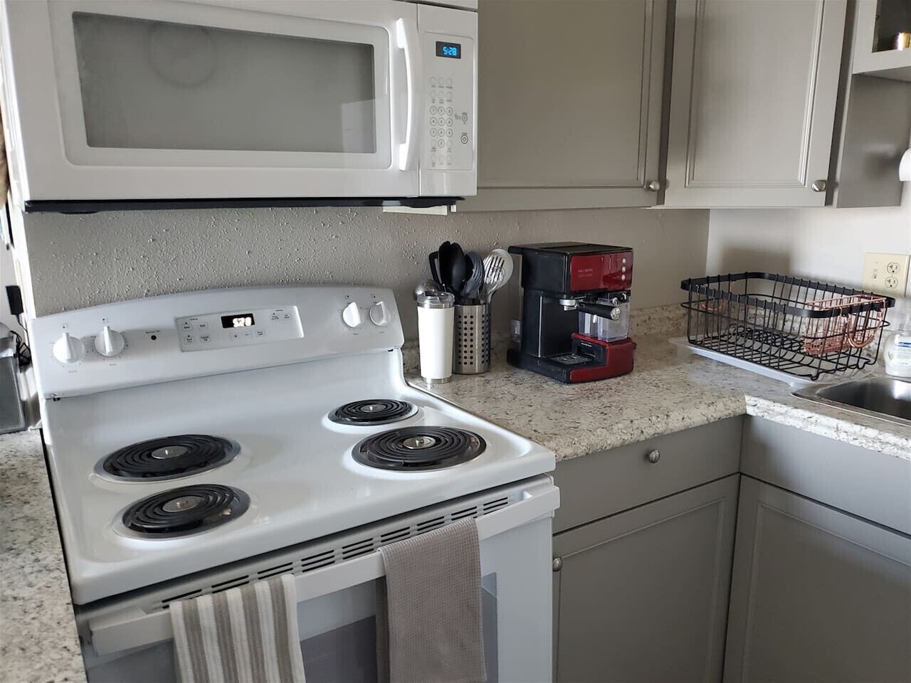 A kitchen with a white stove, a microwave, and a coffee maker.