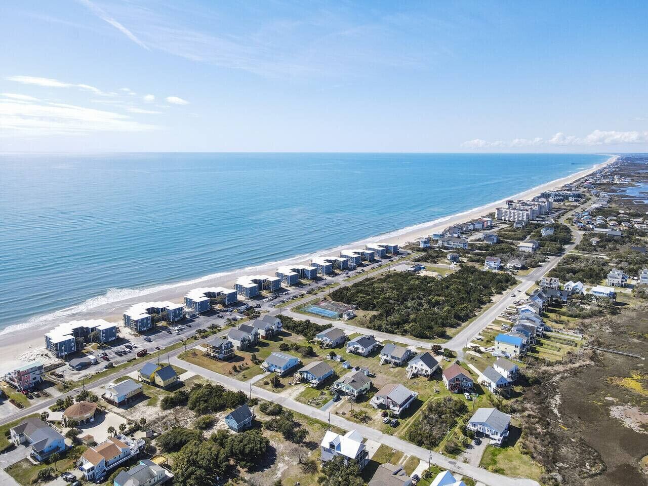 An aerial view of a coastal residential area with houses and a beach.
