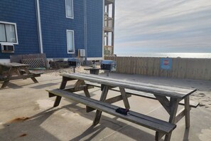 Eine Terrasse am Strand mit Picknicktischen und einem Holzzaun.