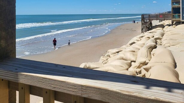 A beach with a wooden boardwalk and a building with multiple balconies overlooking the ocean. - Shore To Please, 1st Floor Oceanfront Condo (North Topsail Beach)
