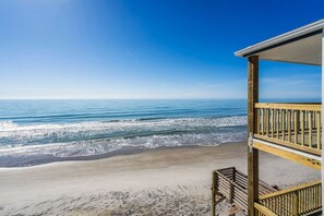 Une vue sur la plage depuis un balcon doté d’une balustrade en bois.