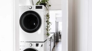 A laundry room with stacked washing machines and a plant hanging above them. - Cozy Private Home, 10-min From DT, Beach & Parks (San Diego)