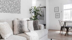 A modern living room with a sofa, a dining table, and a large plant. - Cozy Private Home, 10-min From DT, Beach & Parks (San Diego)