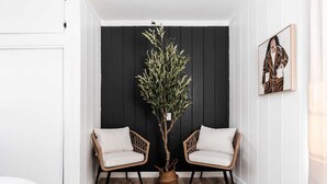 A corner room with two wicker chairs, a potted plant, and a painting on the wall. - Cozy Private Home, 10-min From DT, Beach & Parks (San Diego)