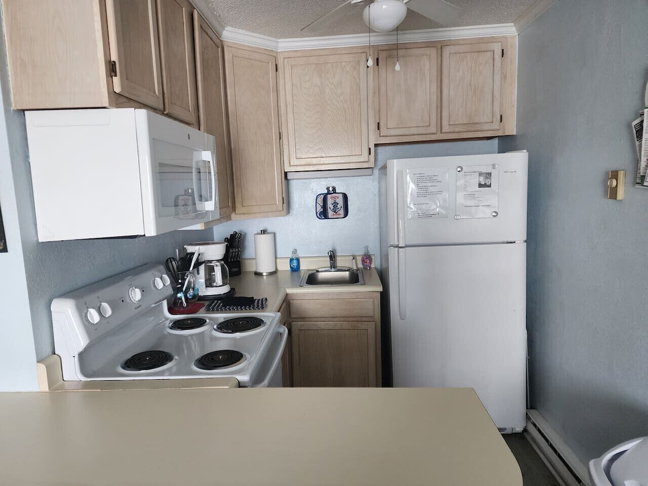 A kitchen with wooden cabinets, a white stove, a microwave, a sink, and a refrigerator.