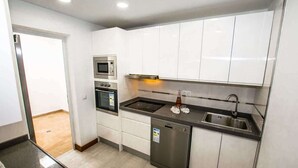 Een moderne keuken met witte kastjes, roestvrijstalen apparatuur en een vaatwasser.