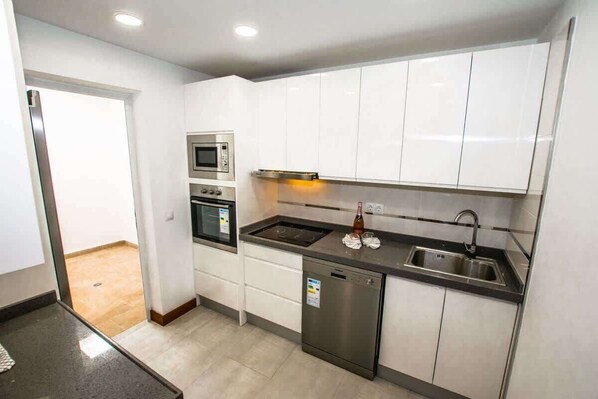 A modern kitchen with white cabinets, stainless steel appliances, and a dishwasher. - Casa Luca - Modern Escape by Villas Now (Playa Blanca)