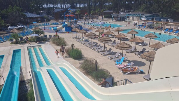 Un parque acuático con múltiples toboganes y una zona de piscina con tumbonas y sombrillas.