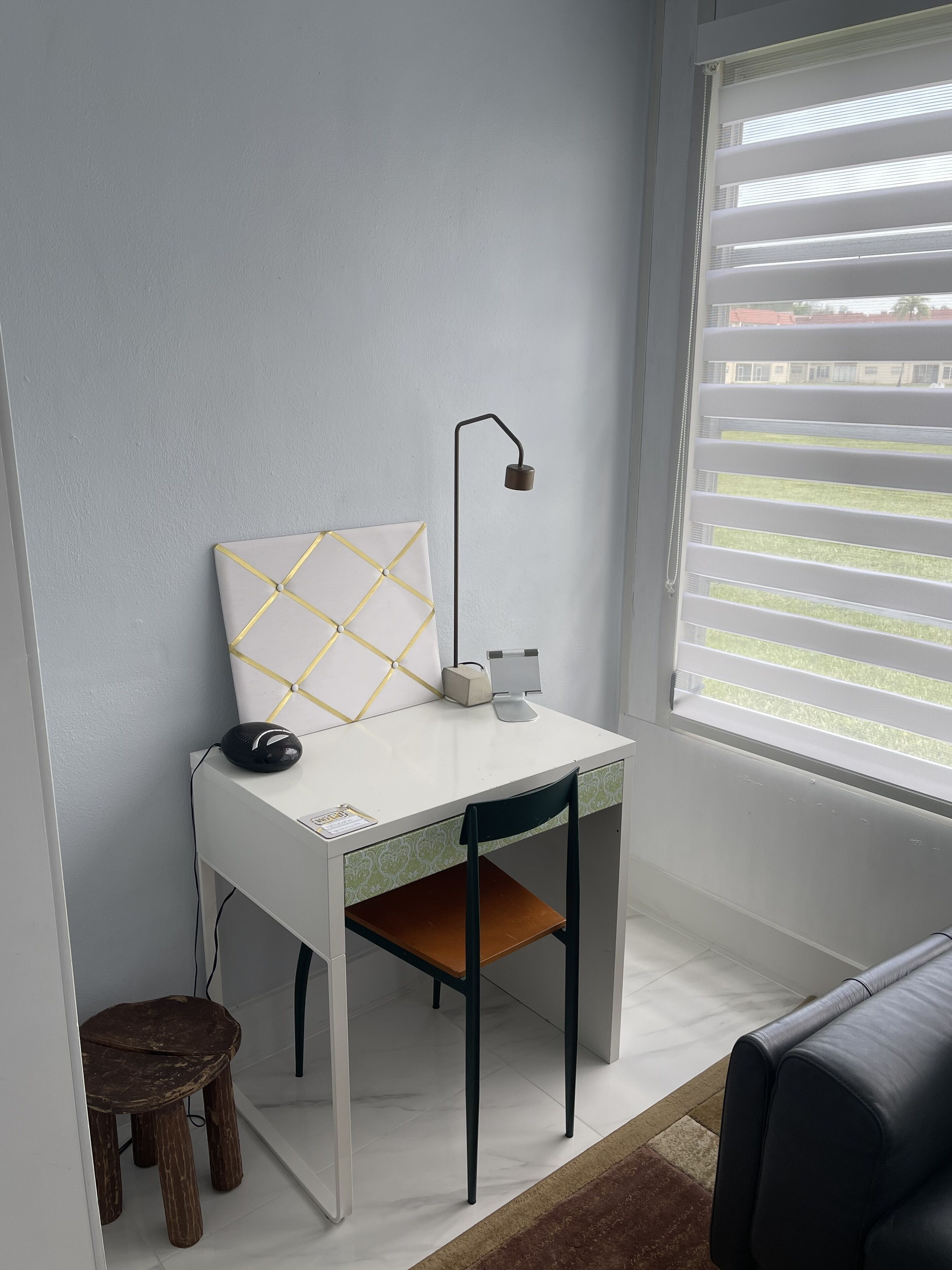 A white desk with a computer mouse, a lamp, and a decorative item against a light blue wall.