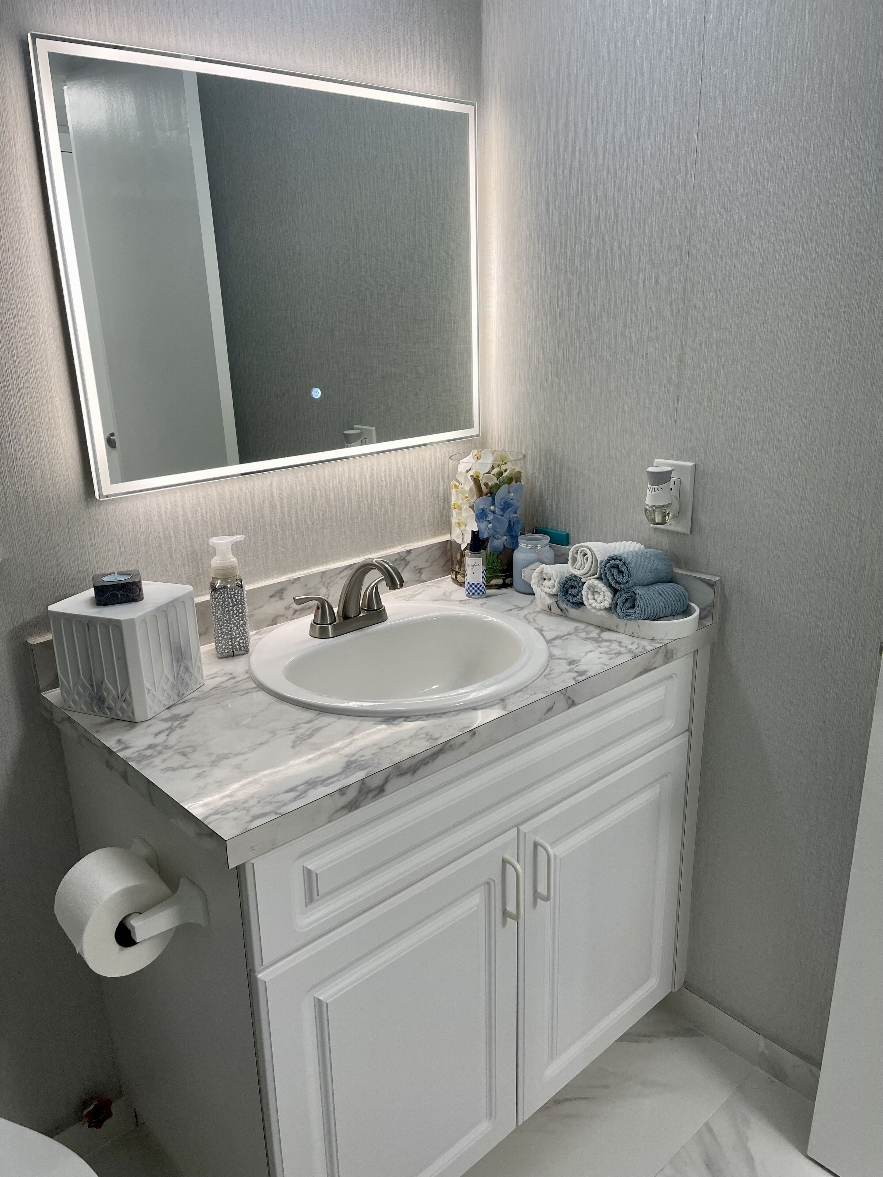 Une salle de bain avec un lavabo blanc, un miroir, un porte-serviettes et des toilettes.