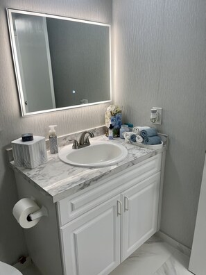 A bathroom with a white sink, a mirror, a towel rack, and a toilet.
