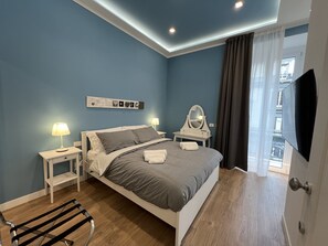 Un dormitorio moderno con cama, mesitas de noche, un espejo y un televisor.