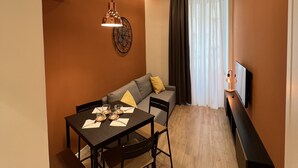 Una sala de estar moderna con comedor, un sofá, un televisor y un aire acondicionado instalado en la pared.
