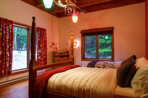 A bedroom with a bed, a dresser, a window with a view of trees, and a chandelier. - A one-of-a-kind artist’s retreat surrounded by nature. Enjoy a private hot tub, pool table, direct access to Val-David–Val-Morin Regional Park trails, and a heated pool in summer. (Val-David)