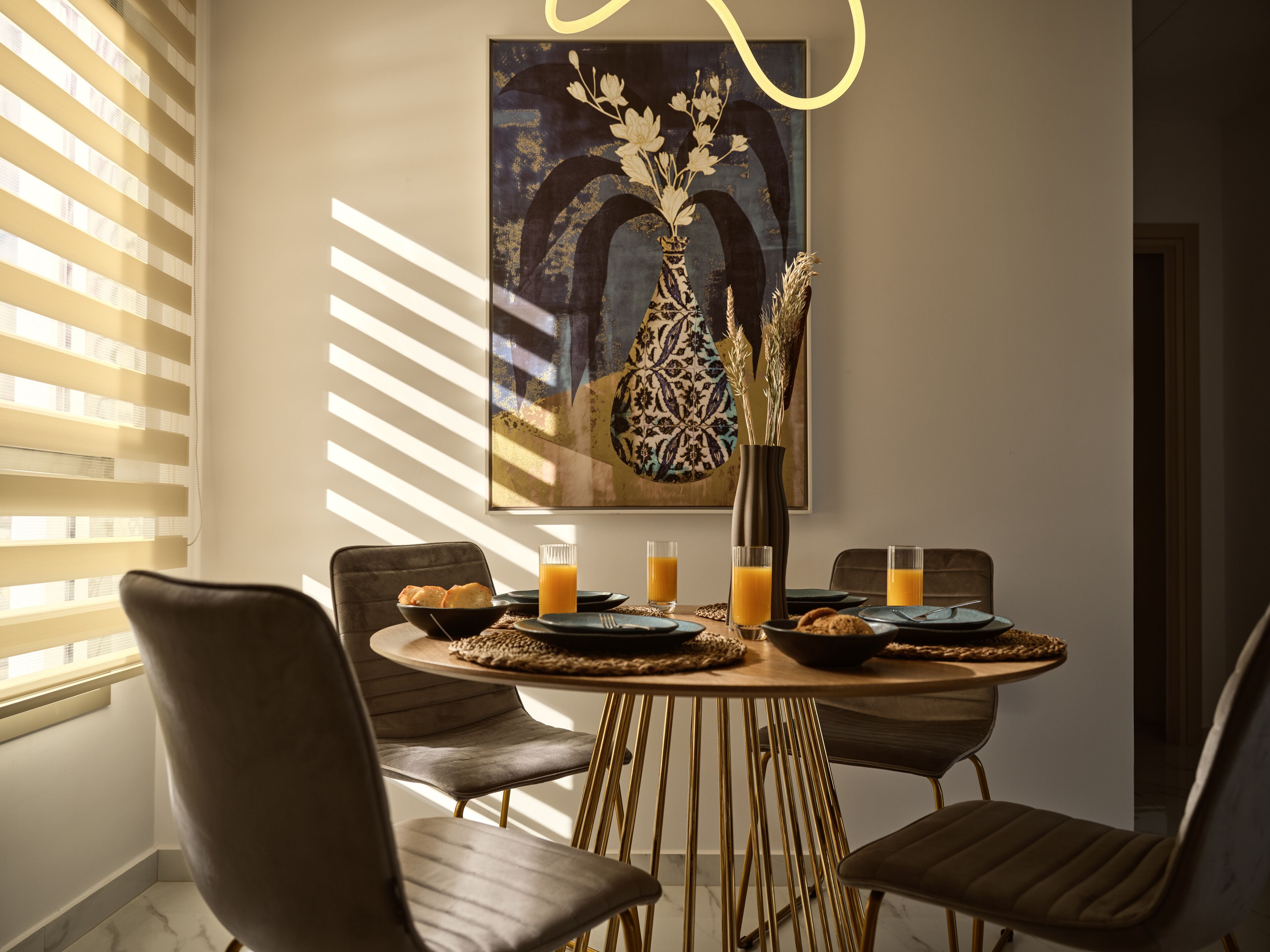 Een eethoek met een ronde tafel, stoelen en een vaas met bloemen.