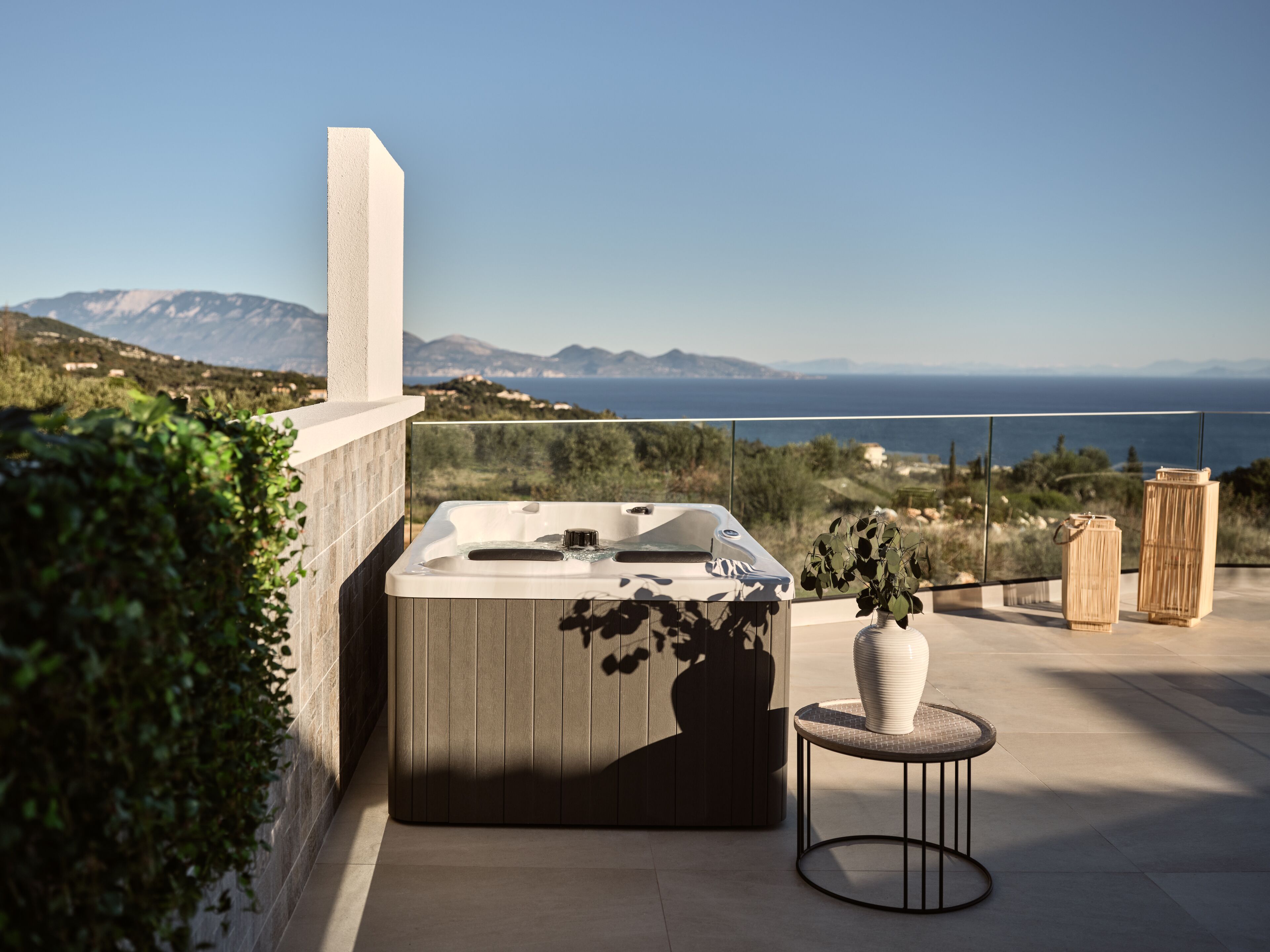 A hot tub on a balcony with a view of the sea and mountains.