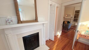 A room with a white fireplace, a large mirror above it, and a wooden floor. - Beautiful historic home in Downtown Murfreesboro-2 bedroom option-sleeps 6 (Murfreesboro)
