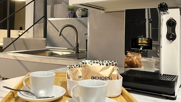 A modern kitchen with a coffee machine, a tray with cups and a bag of coffee, and a staircase. - Appartamento nel Cuore di Napoli (Nápoles)