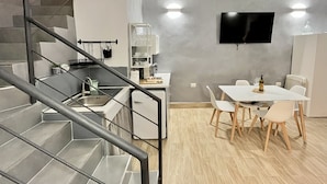 A modern kitchen with a built-in oven, a dining area with a table and chairs, and a staircase with metal railings. - Appartamento nel Cuore di Napoli (Nápoles)